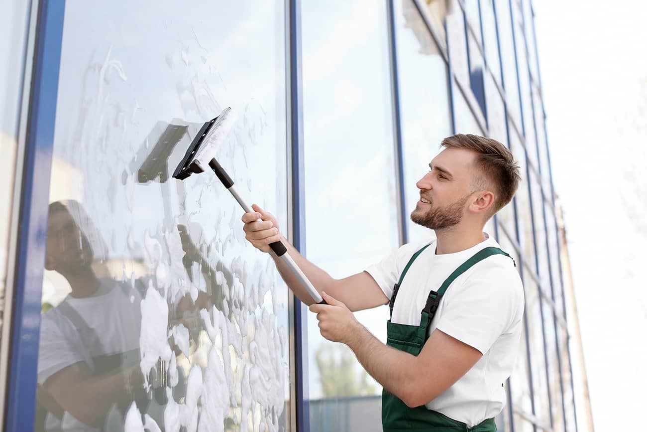 A GlassPro technician cleaning a window with a squeegee