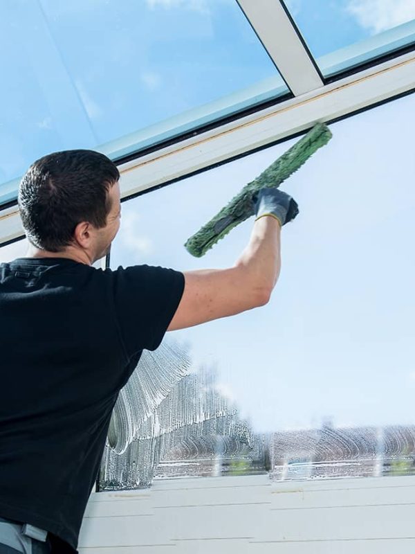 window cleaning professional using squeegee to clean interior commercial windows